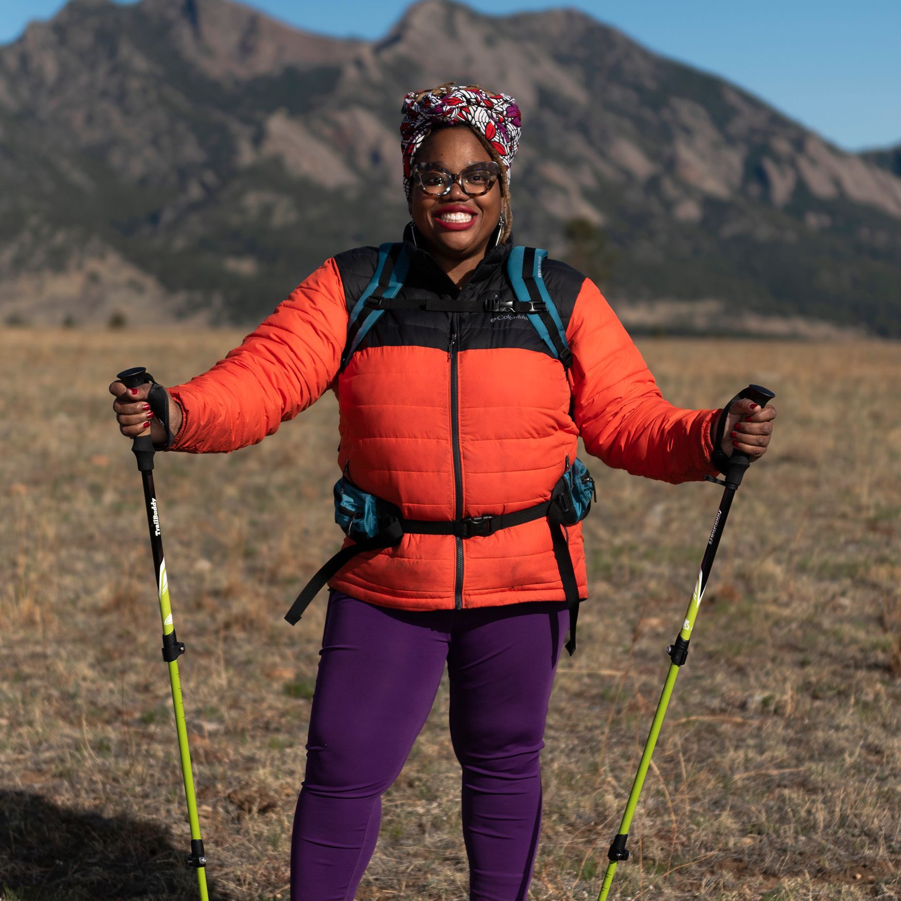 Woman outside in a parka holding hiking poles