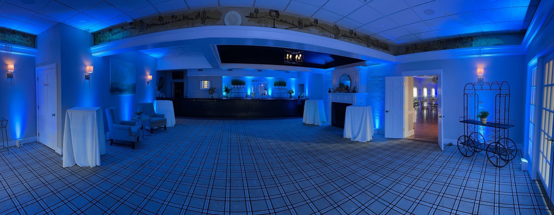 A large room with blue lights on the ceiling and tables and chairs.