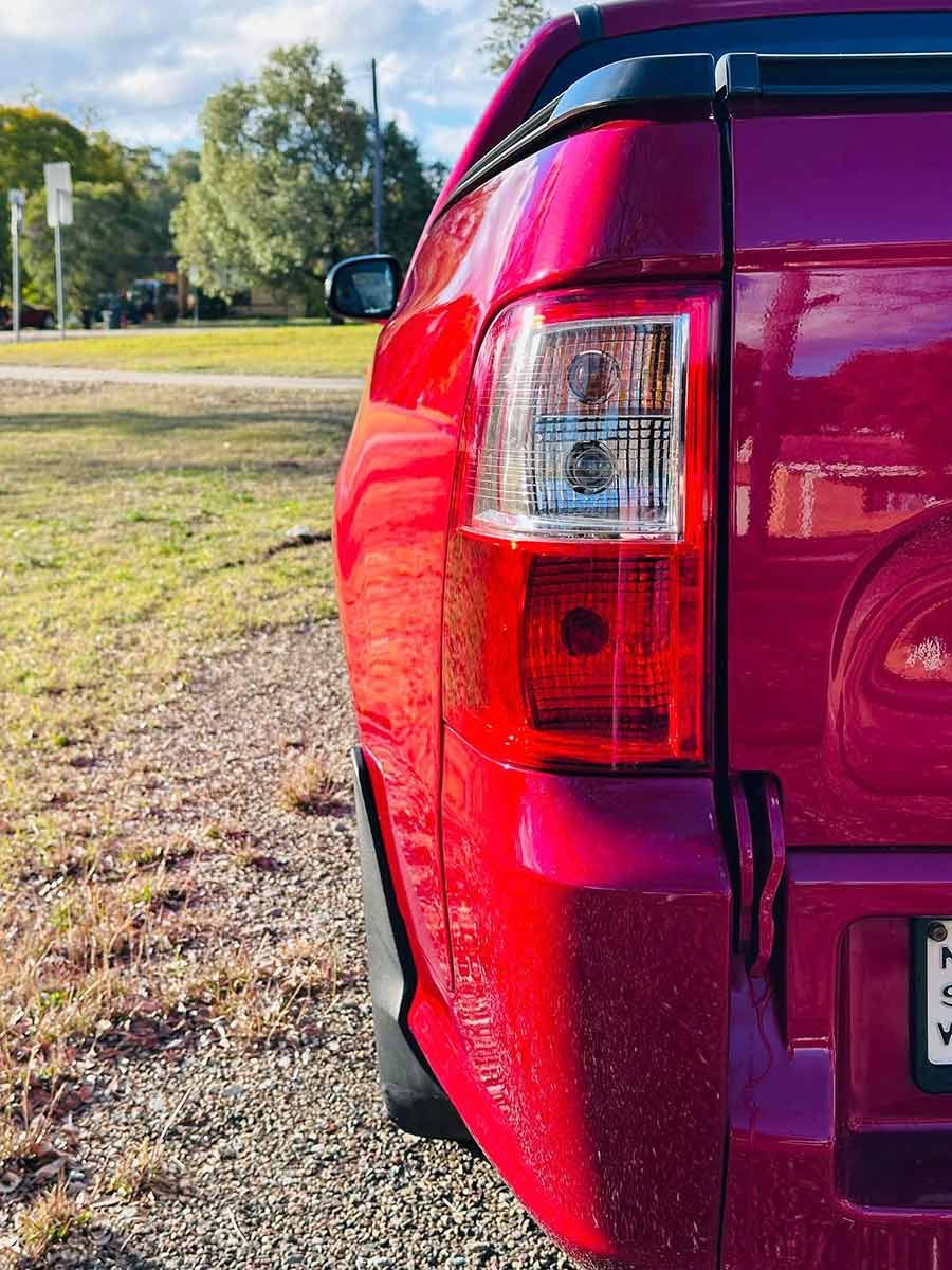 The Left Rear Lights On A Red Ford Falcon Pickup Truck Parked In A Grassy Field.  — Brody’s Car Detailing In Oxley Vale, NSW