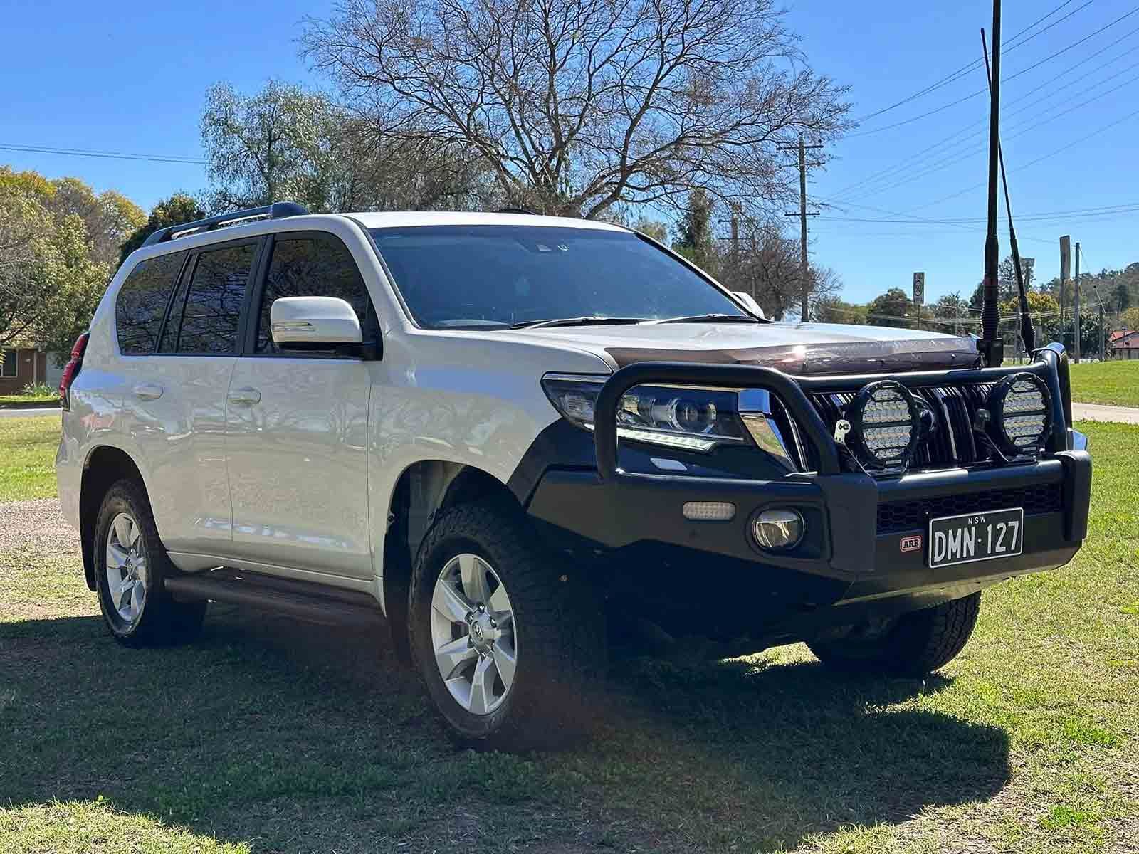 A White SUV With A Black Bumper Is Parked In A Grassy Field — Brody’s Car Detailing In Oxley Vale, NSW