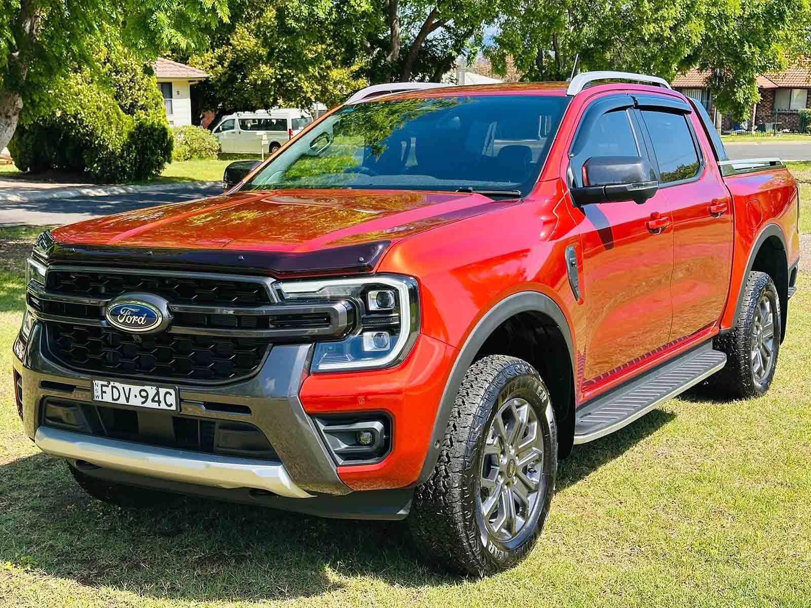 A Red Ford Ranger Is Parked In A Grassy Field — Brody’s Car Detailing In Oxley Vale, NSW
