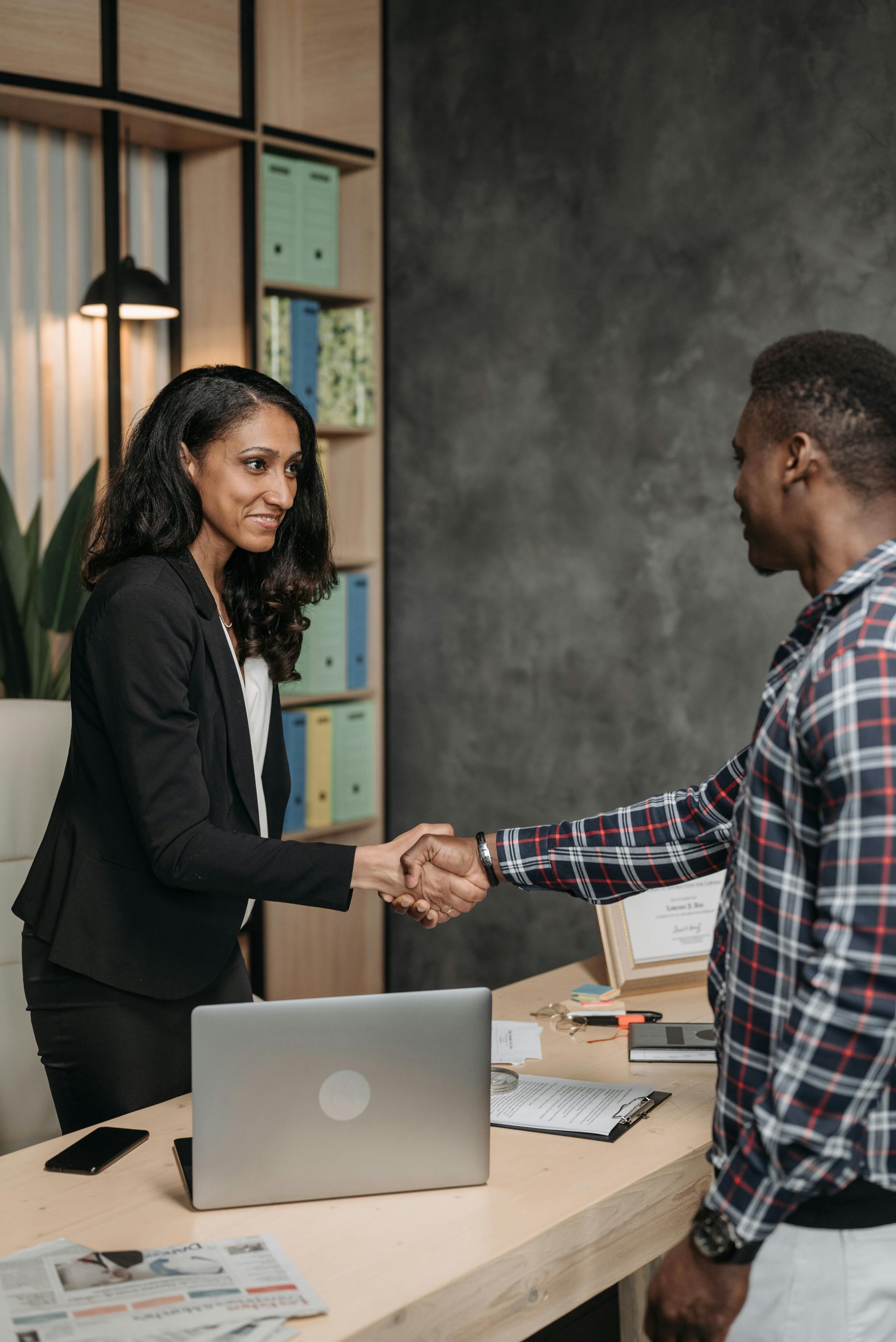 A woman is shaking hands with a man in an office.
