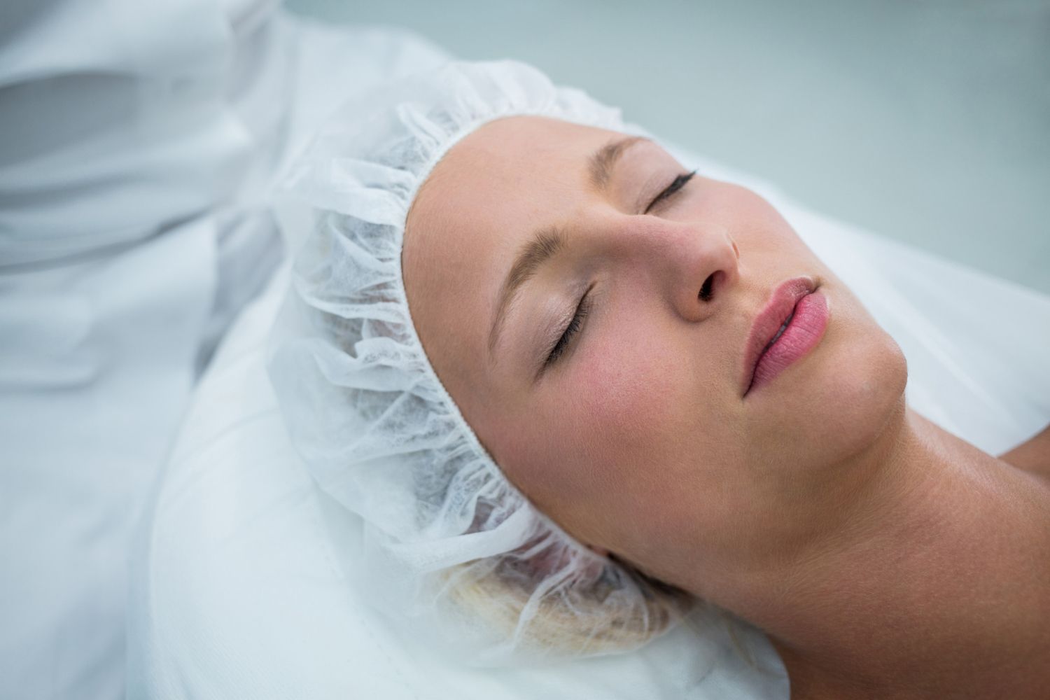 A woman is laying on a bed with her eyes closed and wearing a plastic cap.