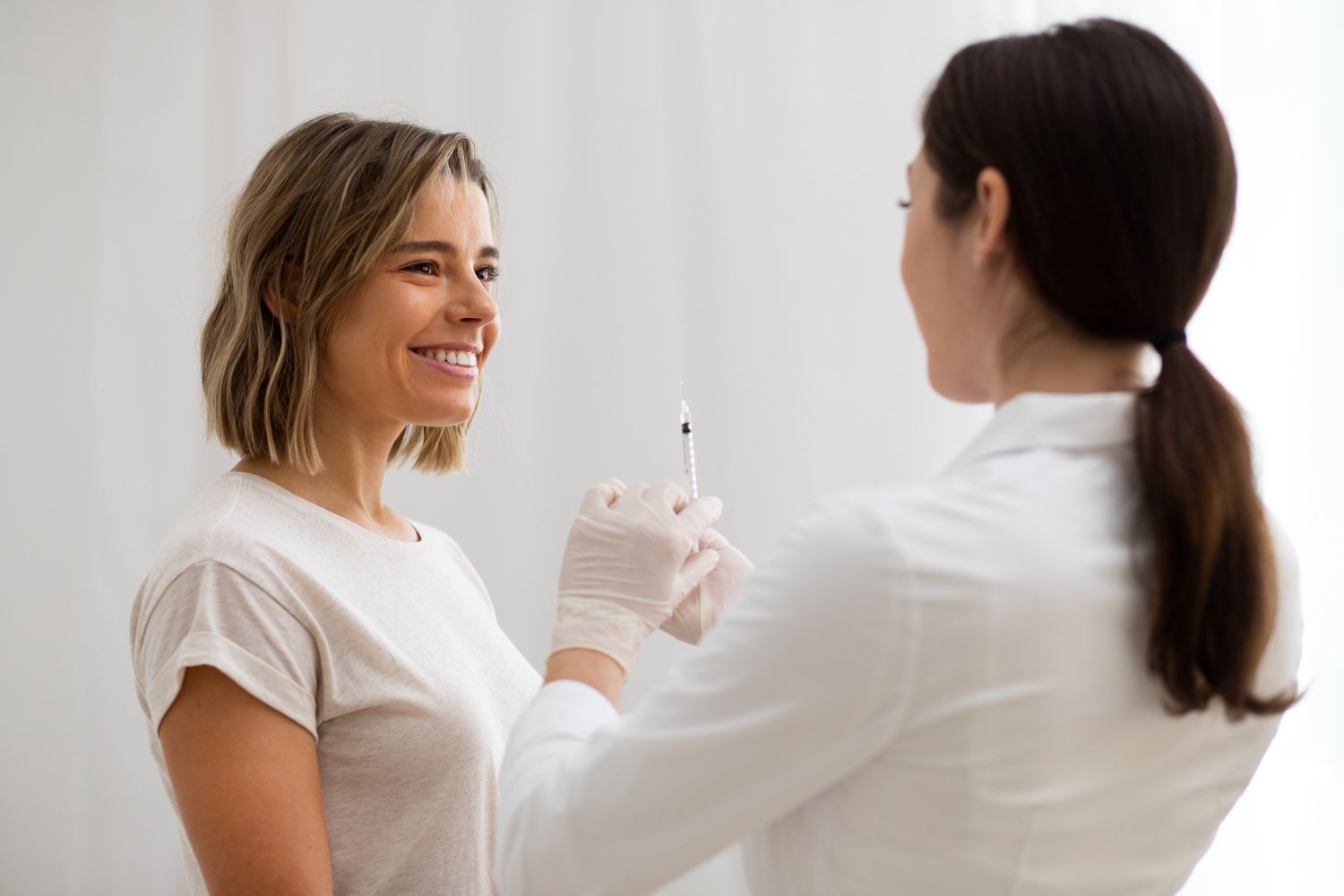 A woman is smiling while getting an injection from a doctor.