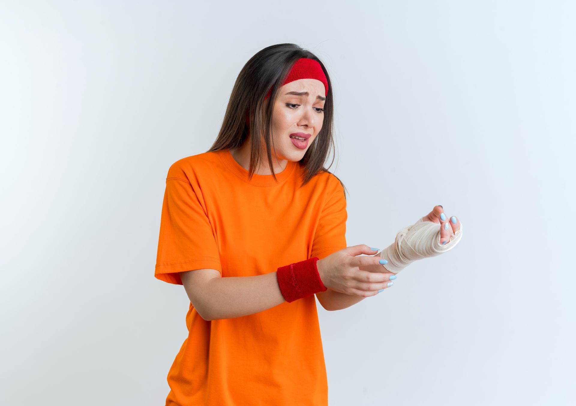 Woman in orange shirt with bandaged wrist, appears to be in pain, red headband.