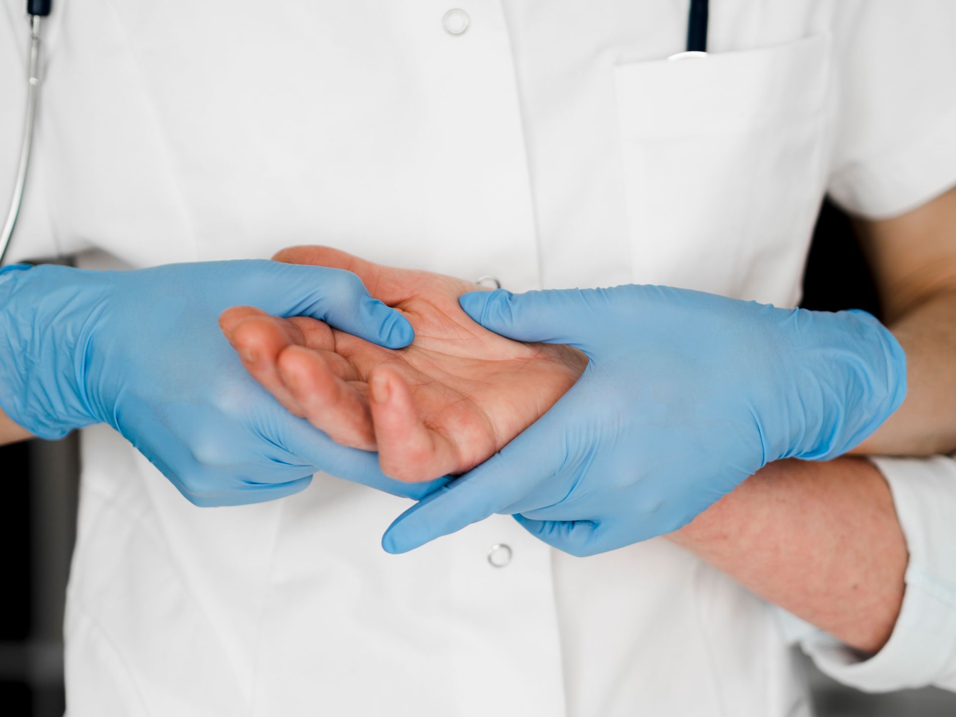 A doctor wearing blue gloves is examining a patient 's hand.