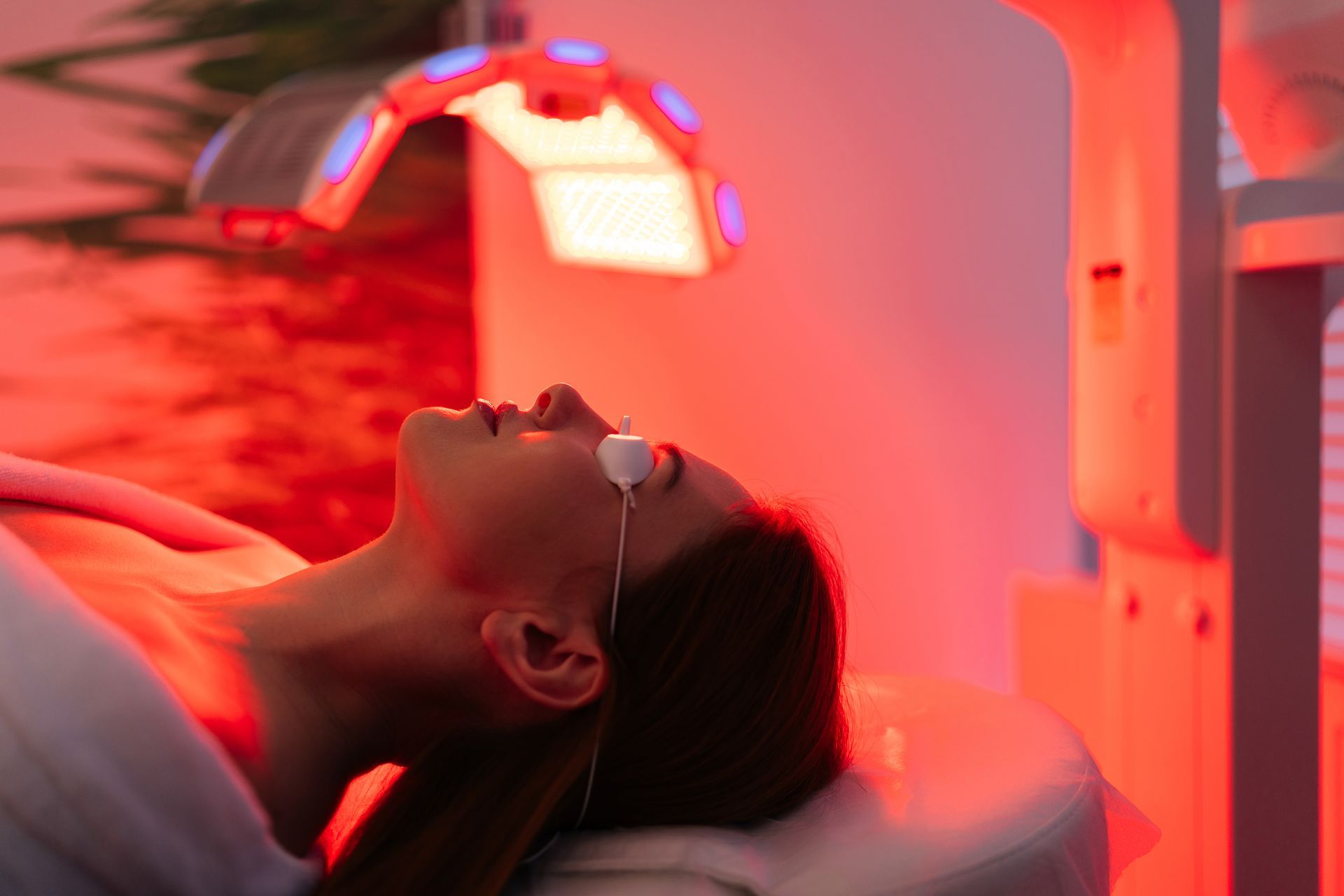 Woman undergoing red light therapy with eye protection in a spa setting.