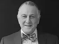 Man in suit and bowtie smiles at the camera.