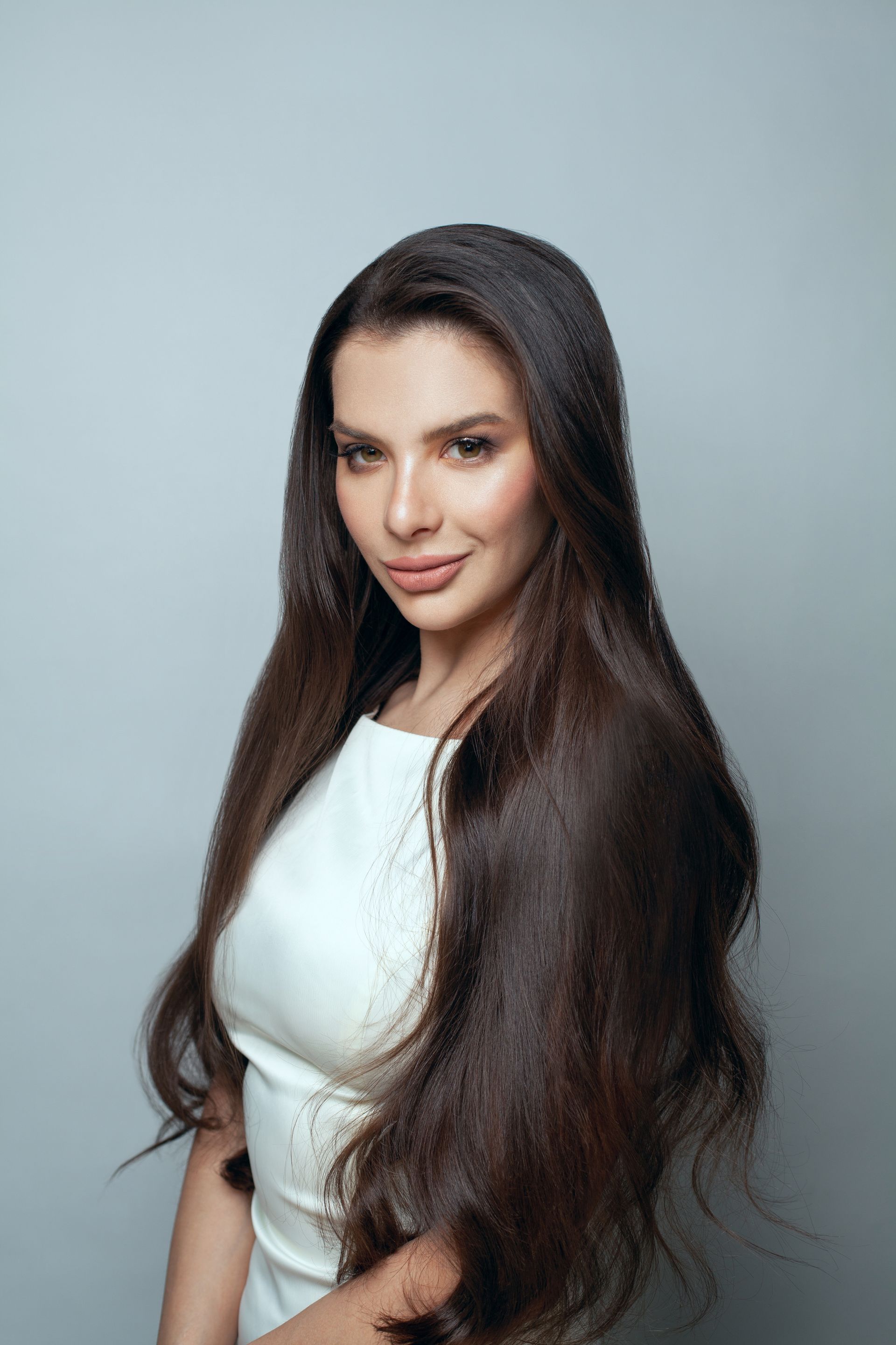 A woman with very long hair is wearing a white dress.