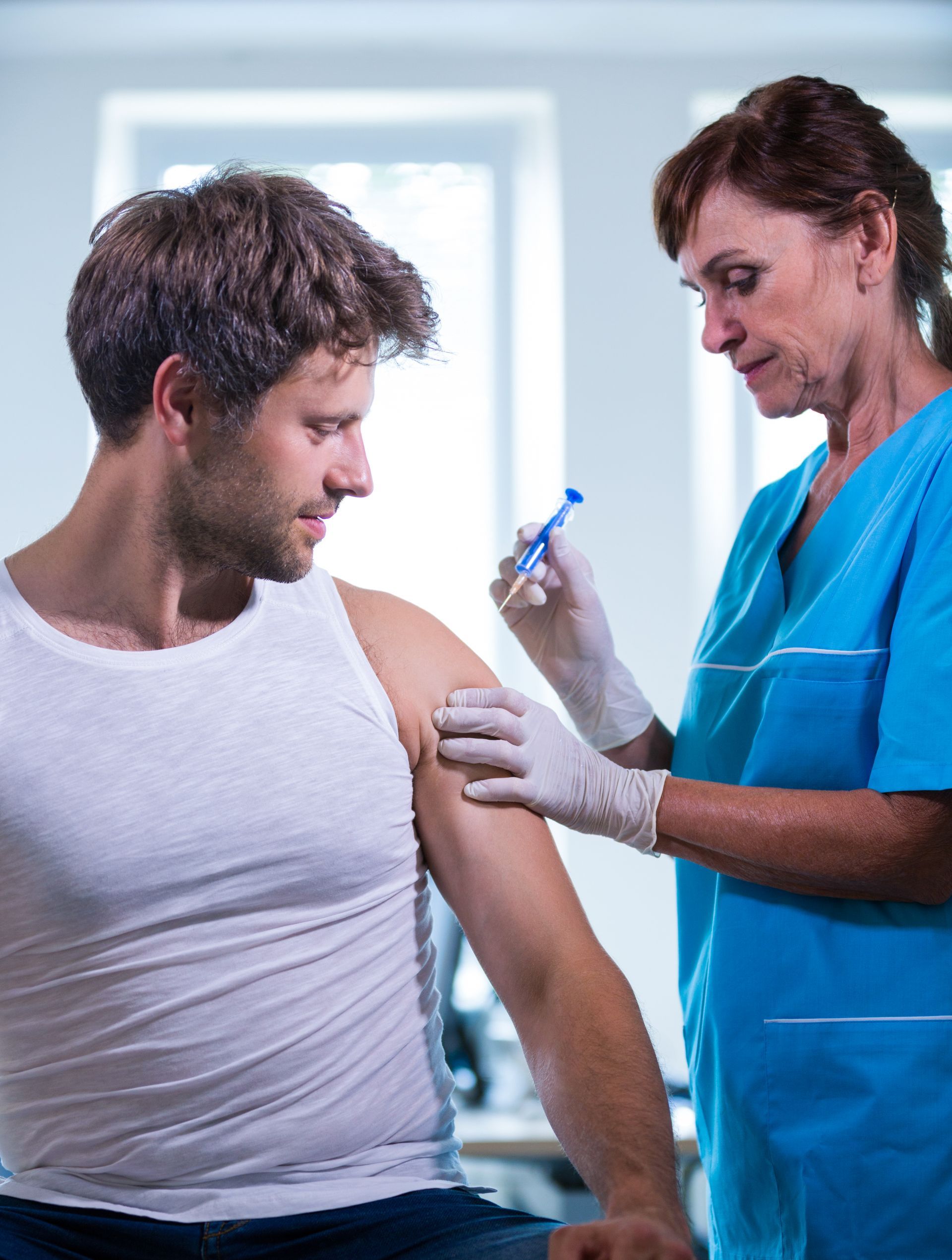 A healthcare worker giving a shot in the arm to a patient.