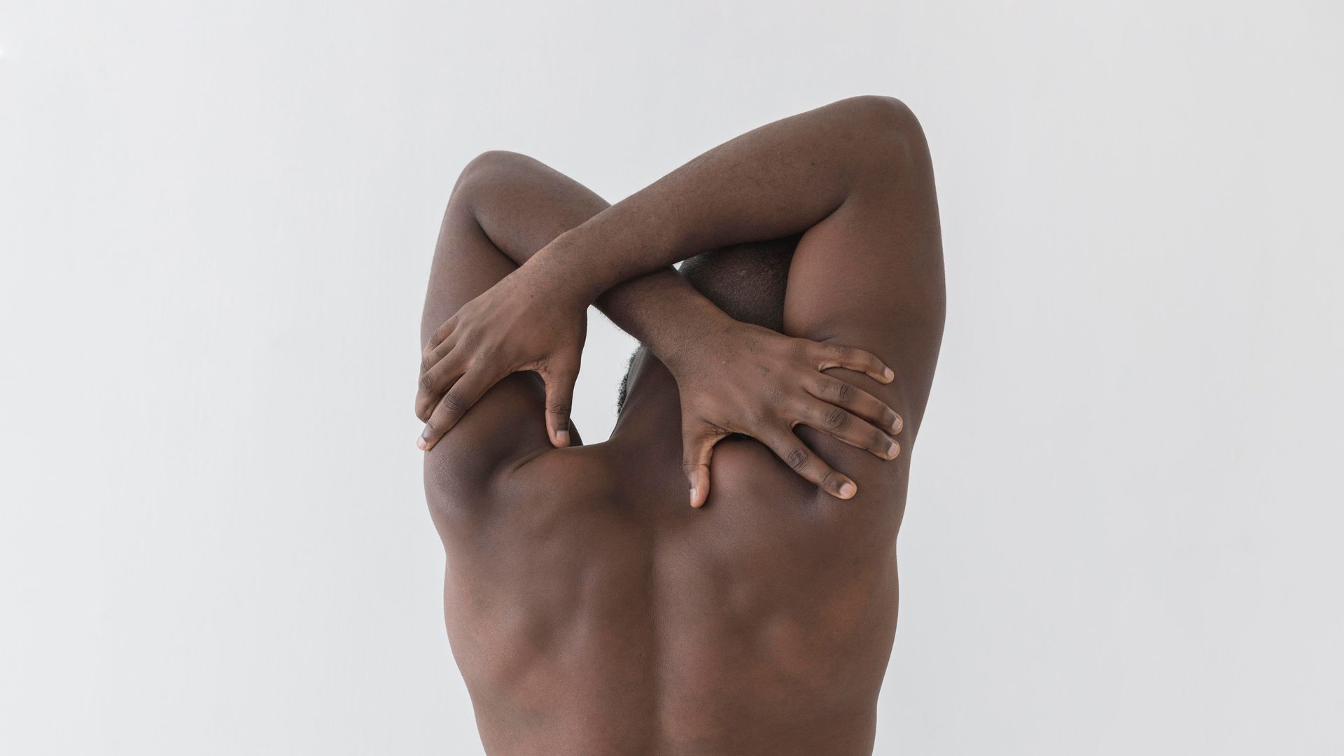 a shirtless man is stretching his arms against a white background .