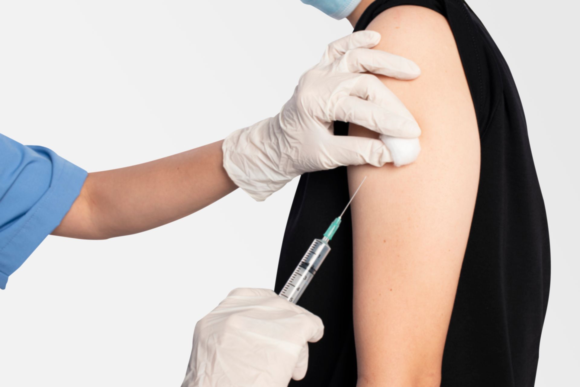 A person receiving a vaccine injection in their upper arm; a medical worker administers the shot.