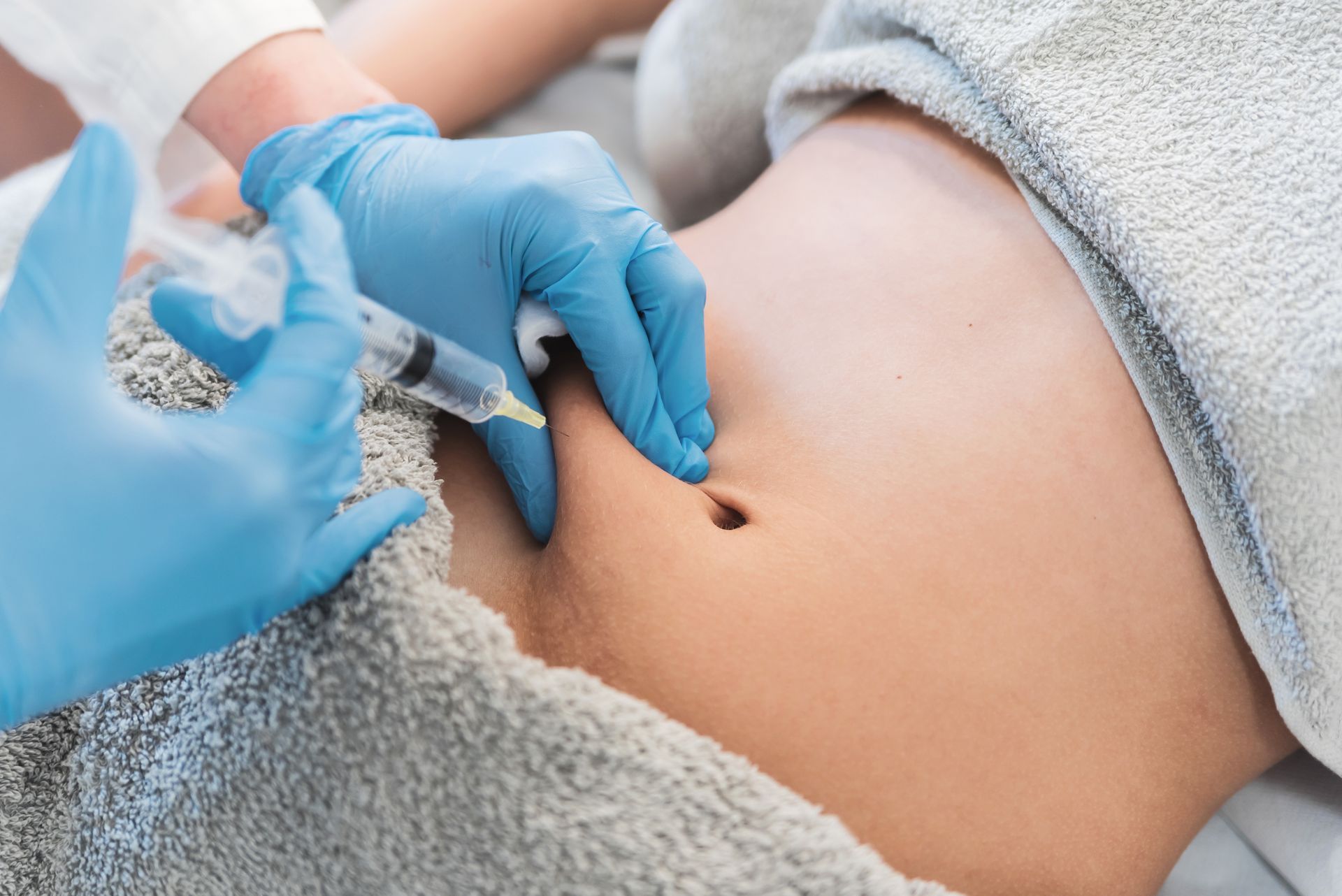 A woman is getting an injection in her stomach.