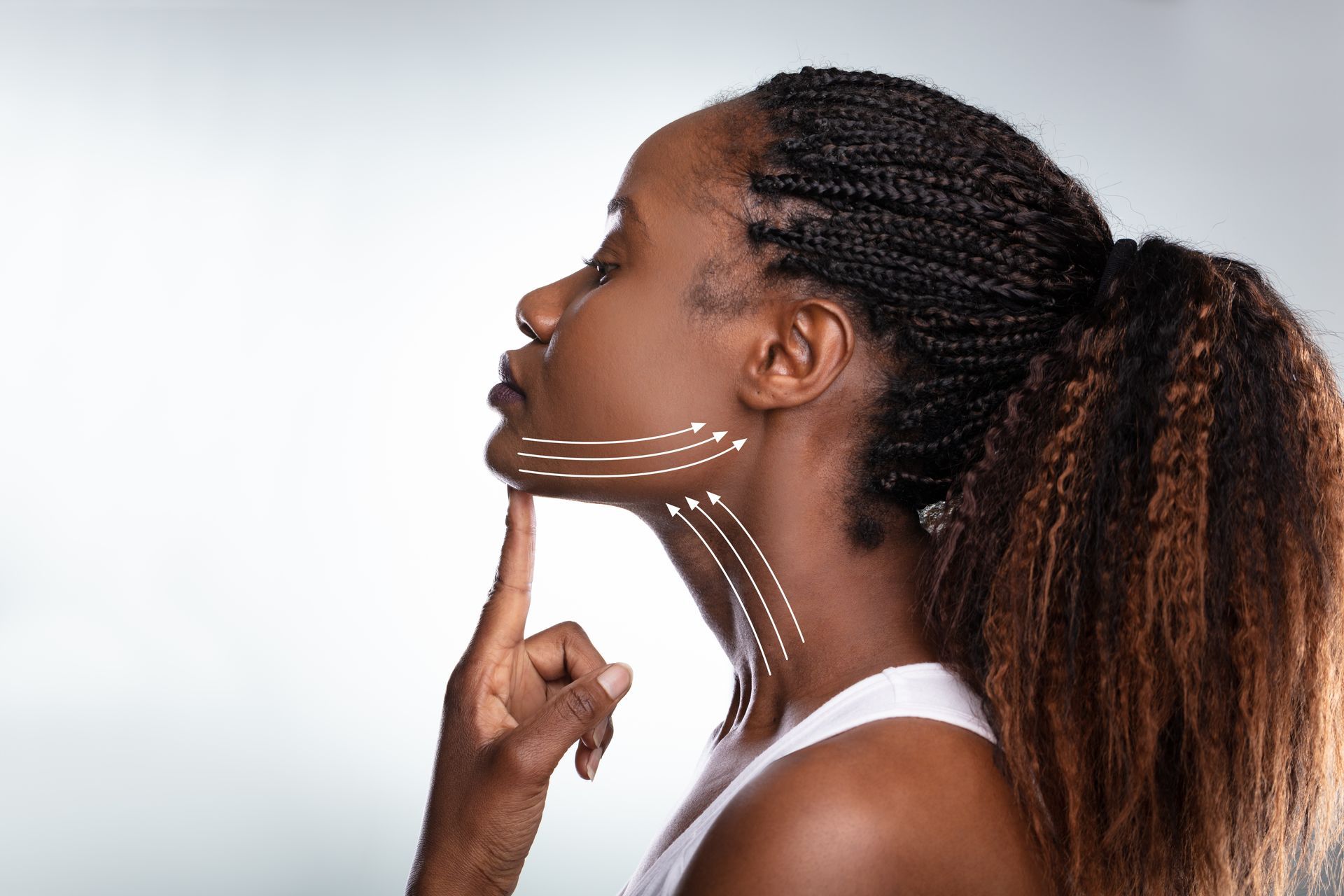 Woman with braids pointing at chin, white arrows show skin tightening.