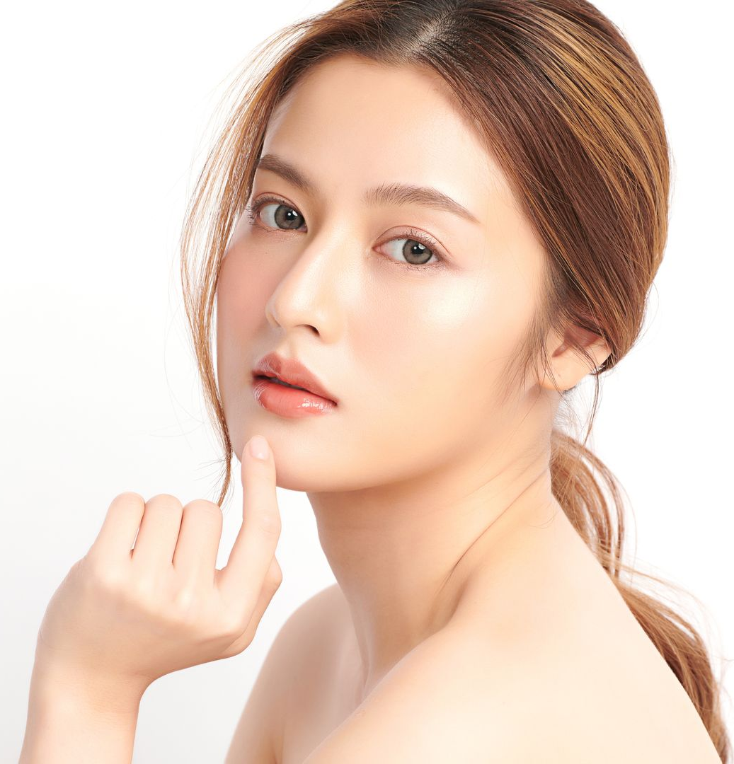 Woman with fair skin, gazing at the camera, hand on her chin, against a white backdrop.