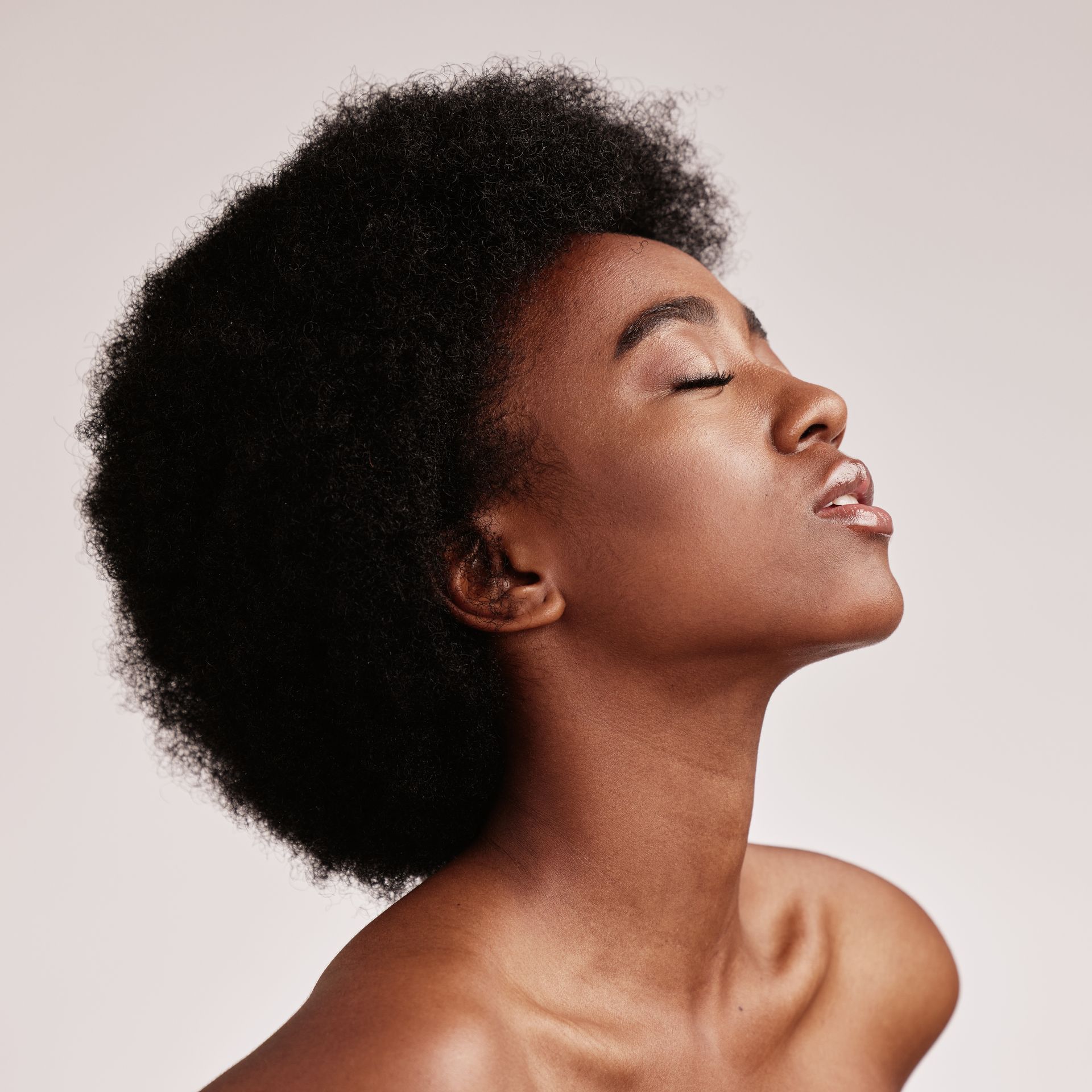 a woman with an afro is looking up with her eyes closed