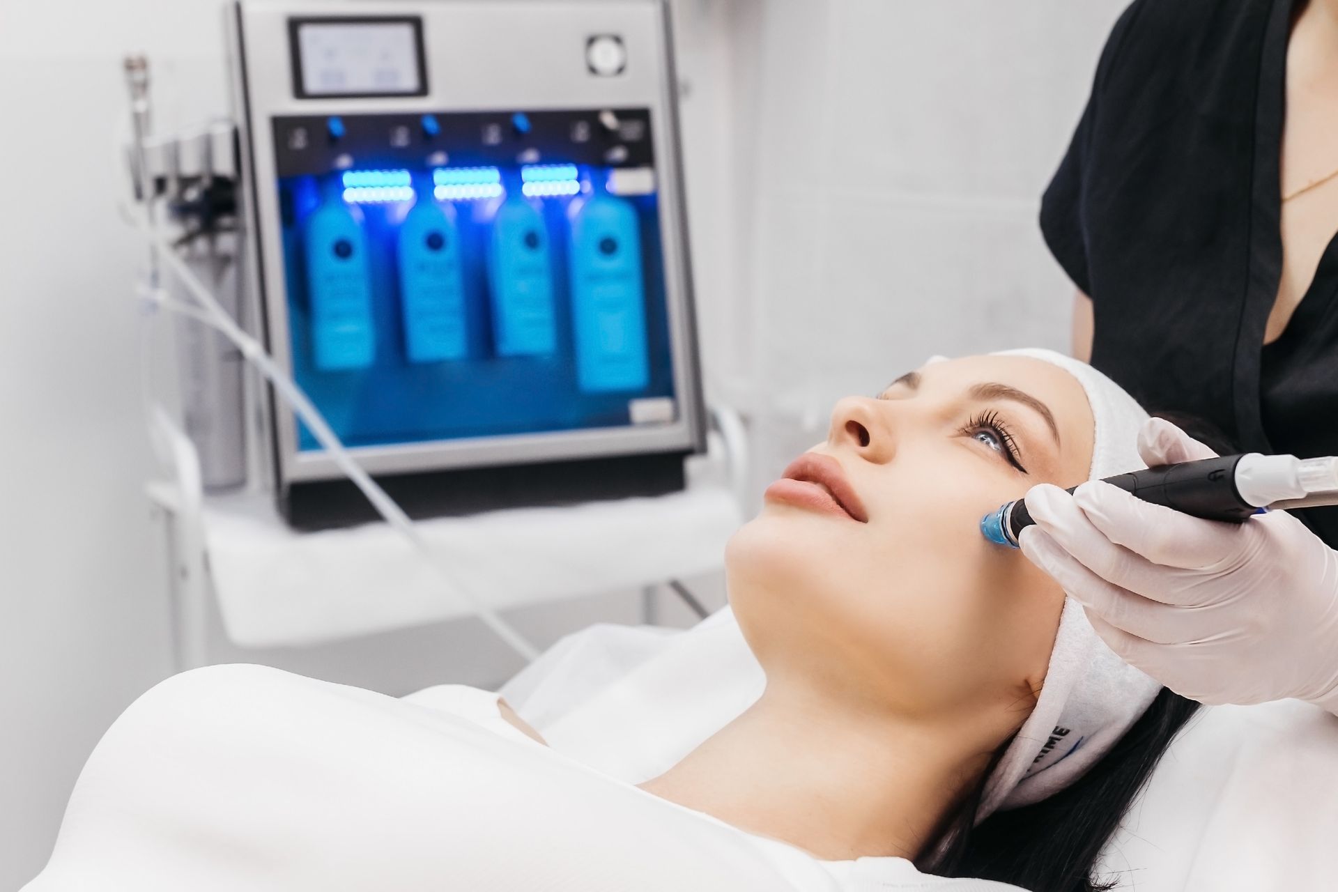 Woman receiving facial treatment with a machine in a bright clinic.