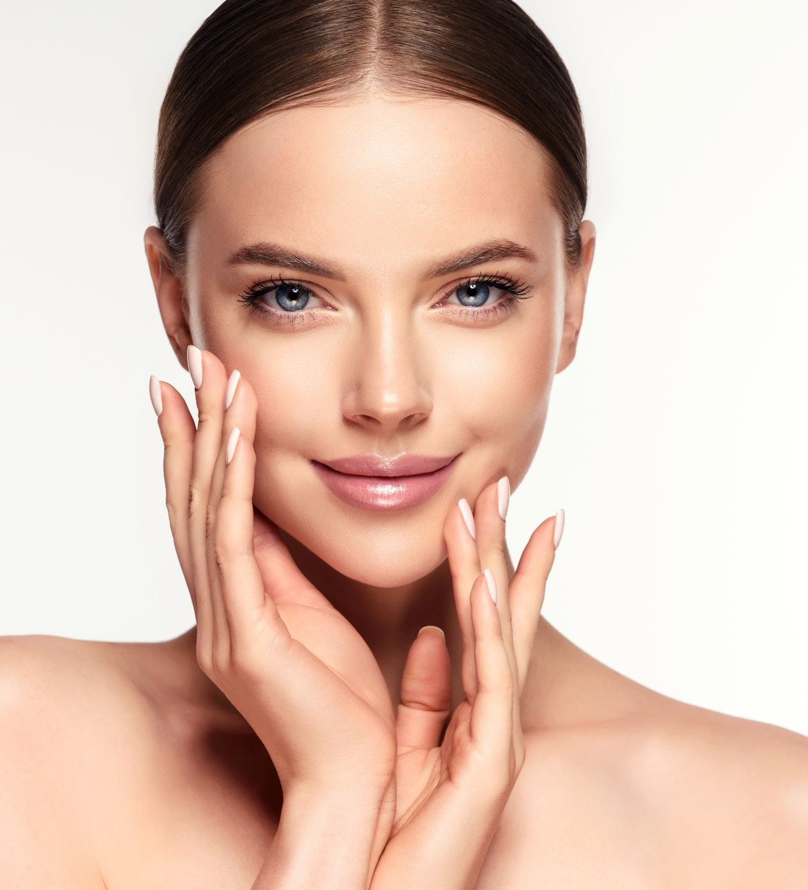 Woman with fair skin touches her cheeks, smiling, with a white background.