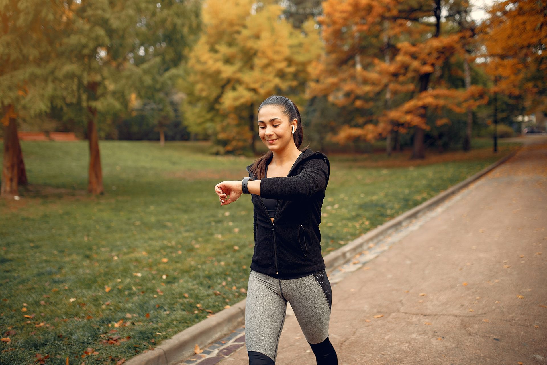 Woman in athletic wear checking smartwatch while walking outdoors.