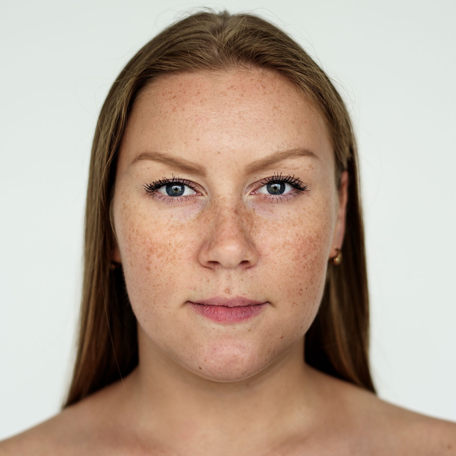 Woman with fair skin and freckles, looking directly at the viewer against a plain white background.