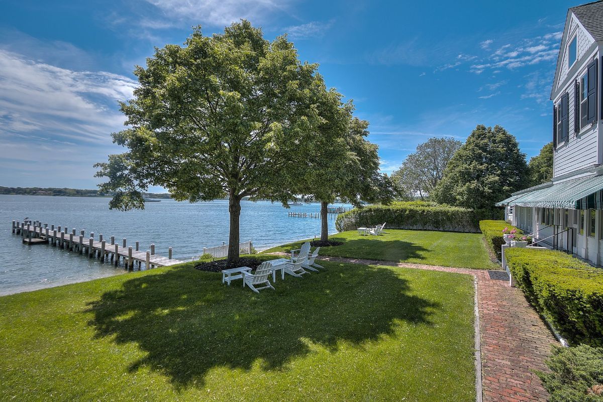 A large lawn next to a body of water with a dock and trees.