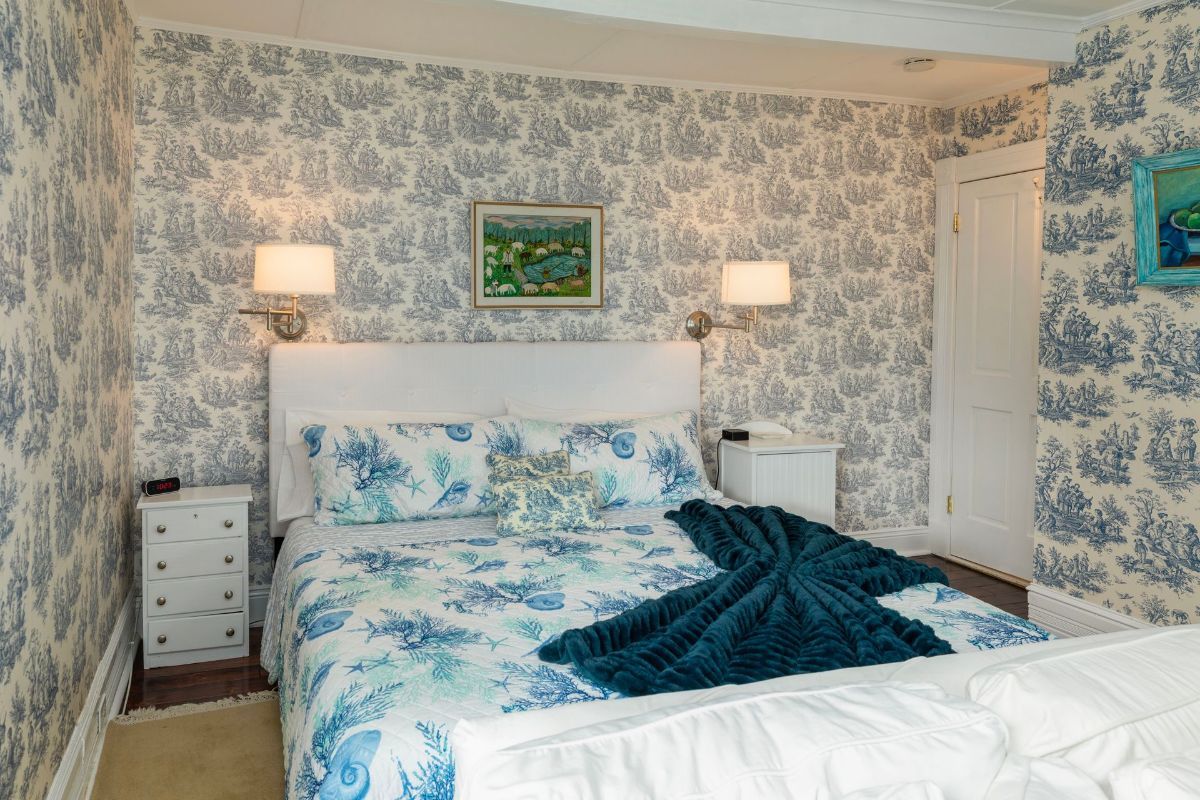 A bedroom with a bed , two nightstands , and blue and white wallpaper.
