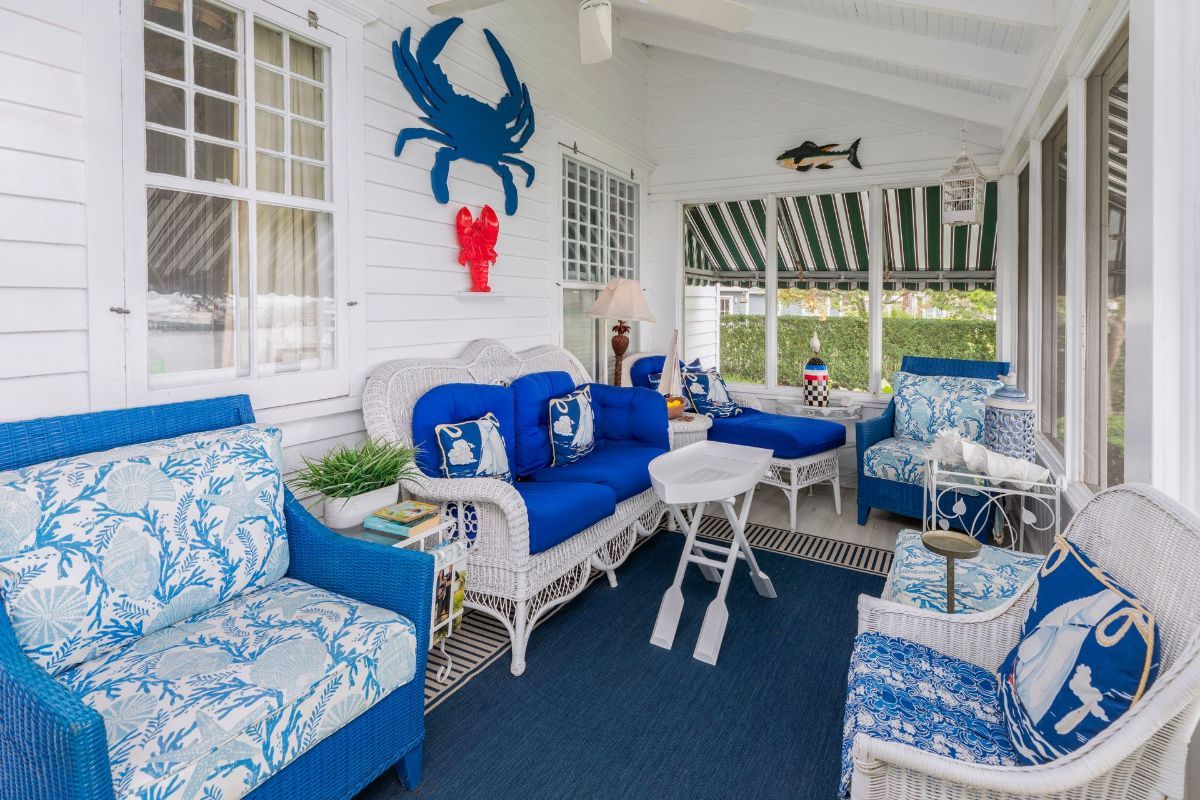 A porch with blue and white furniture and a crab on the wall.
