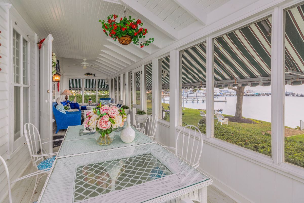 A screened in porch with a table and chairs and a view of the water.
