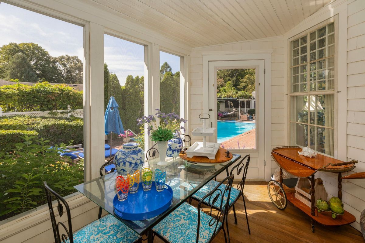 A sun room with a table and chairs and a view of a pool.