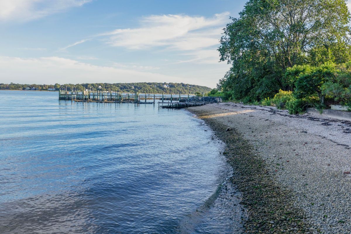A sandy beach next to a body of water with a dock in the background.