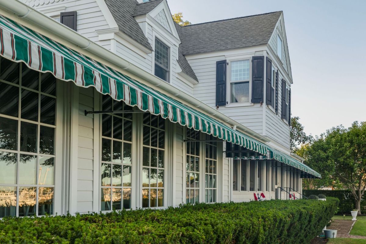 A white house with a green and white awning on the side
