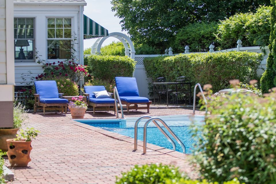A large swimming pool surrounded by blue chairs and a brick patio.