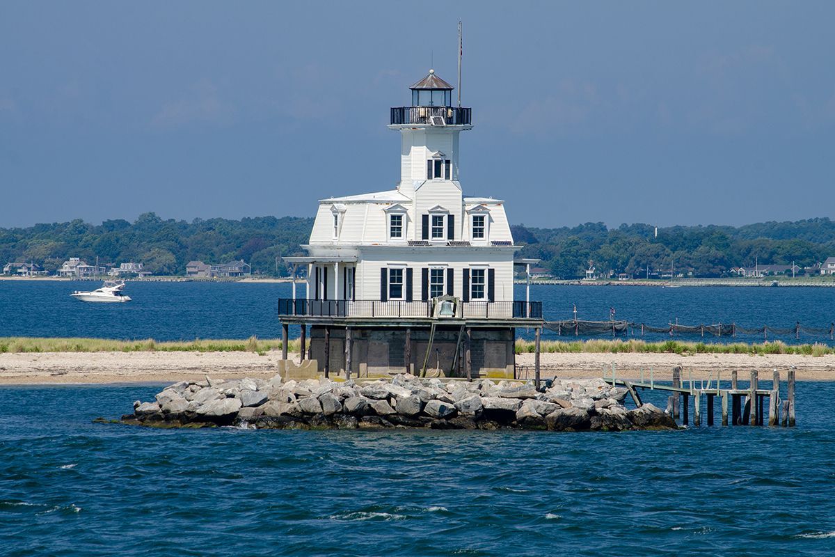 A lighthouse is sitting on top of a small island in the middle of the ocean.