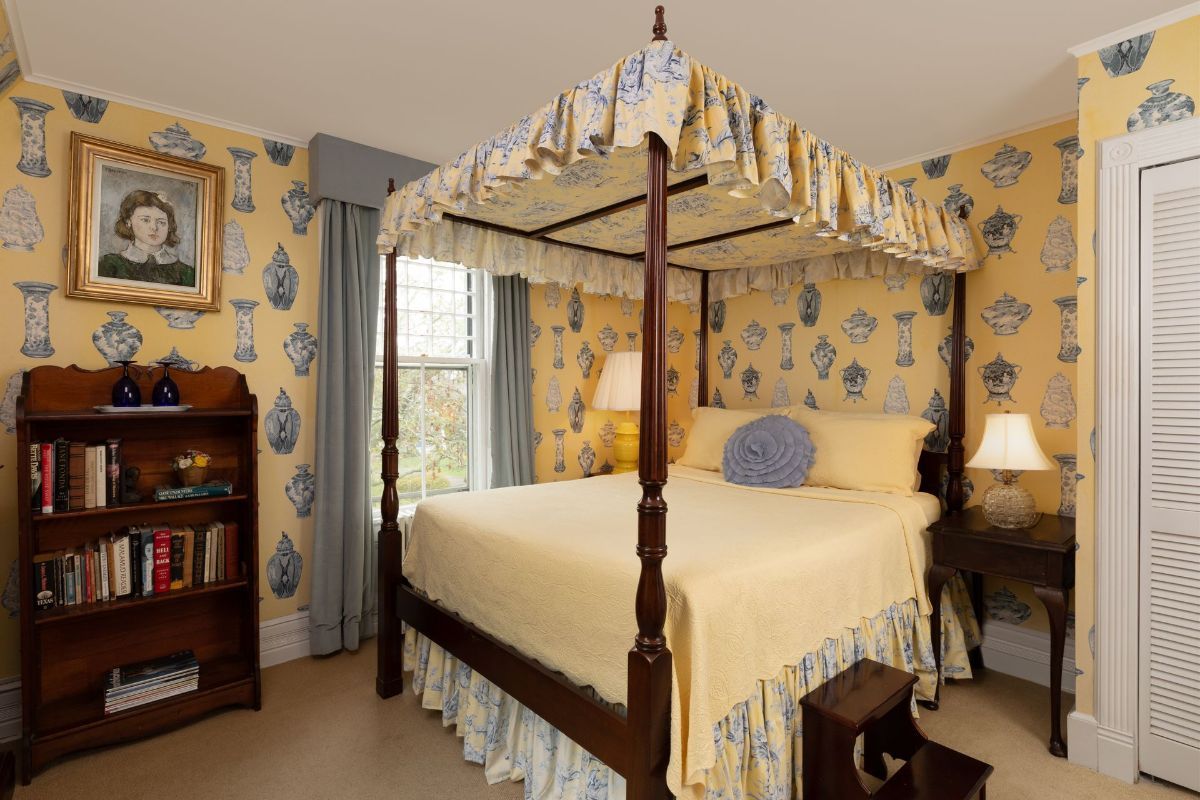 A bedroom with a four poster bed and a bookshelf