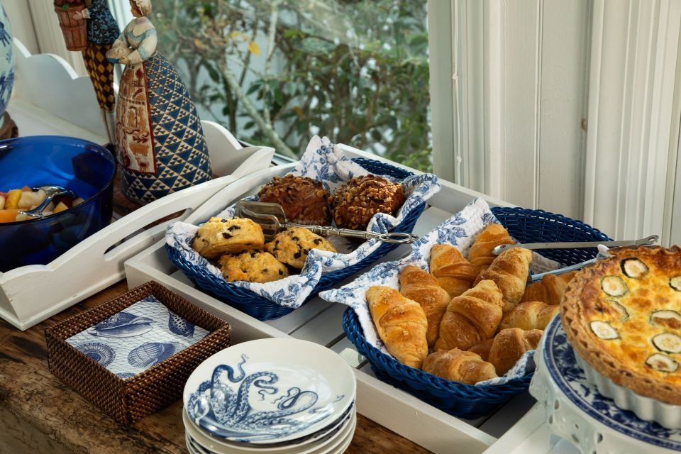 A table topped with a variety of food including croissants and a quiche.