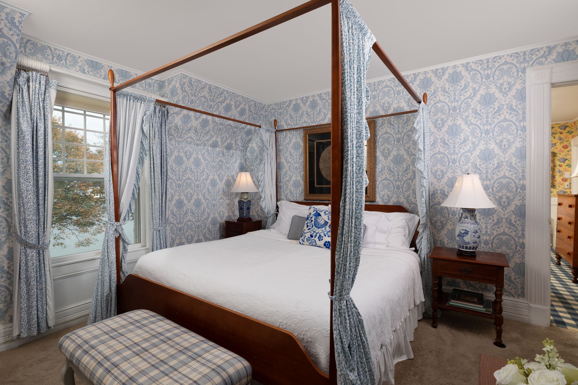 A bedroom with a four poster bed and blue and white wallpaper