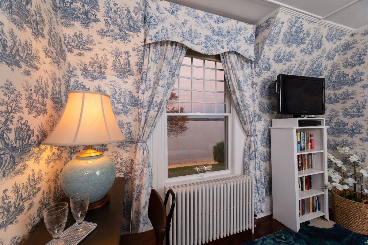 A living room with blue and white toile de jouy wallpaper