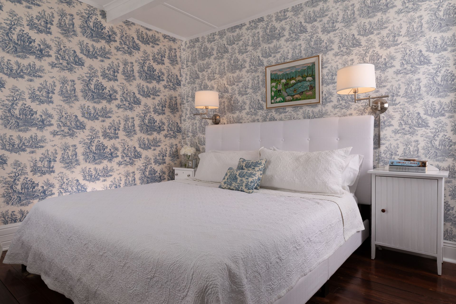 A bedroom with a white bed and blue and white wallpaper