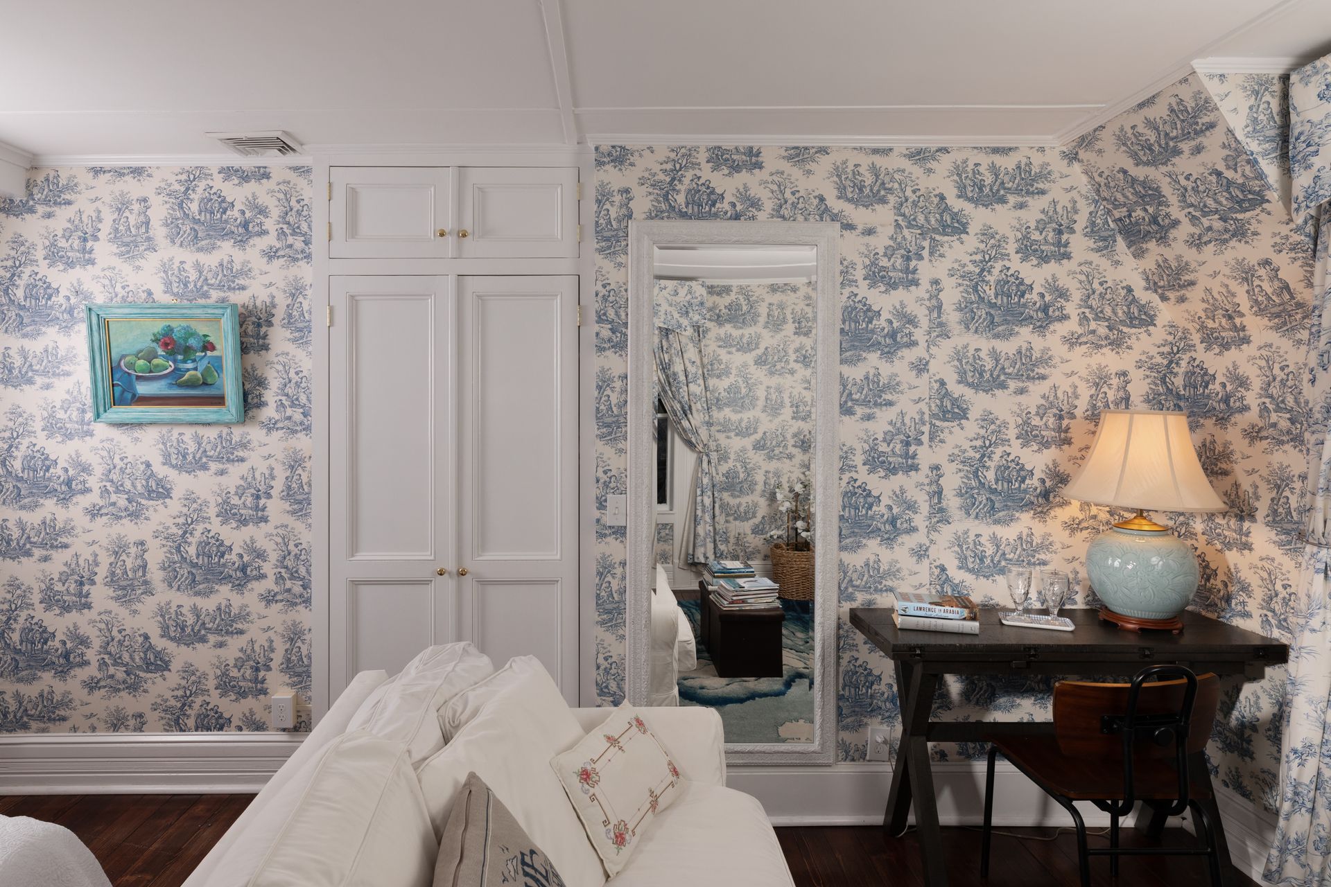 A living room with blue and white toile de jouy wallpaper