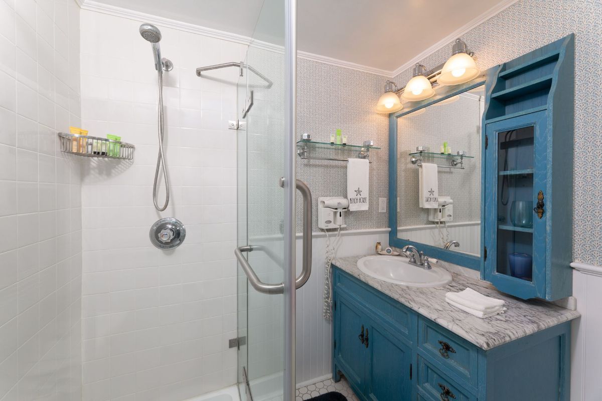 A bathroom with a sink , mirror and shower.