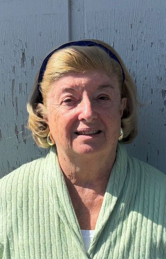 A woman in a green sweater and headband is smiling for the camera.