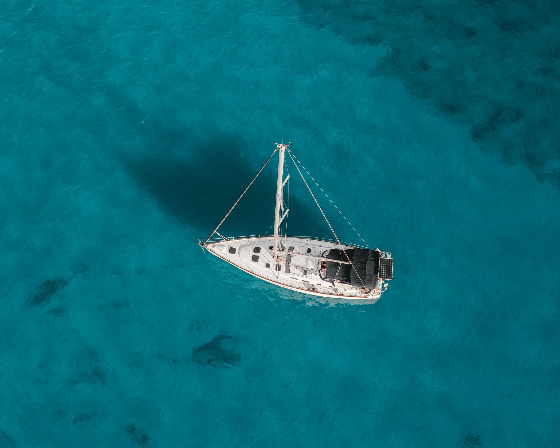 An aerial view of a sailboat in the ocean.