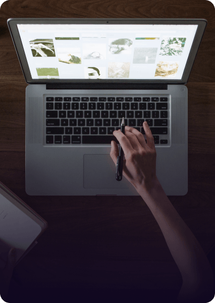 A person is typing on a laptop with a pen