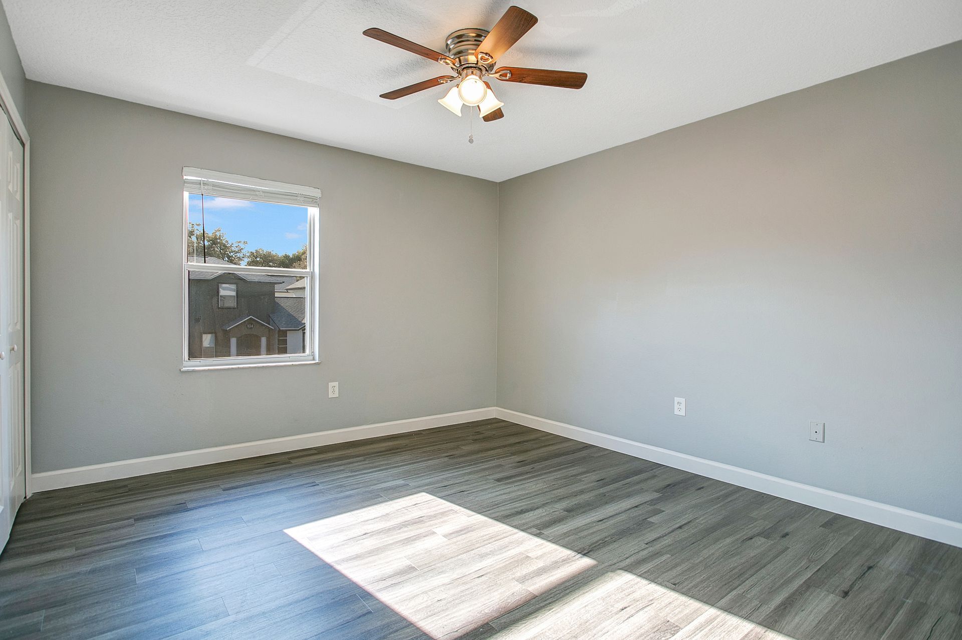 An empty bedroom with a ceiling fan and a window.
