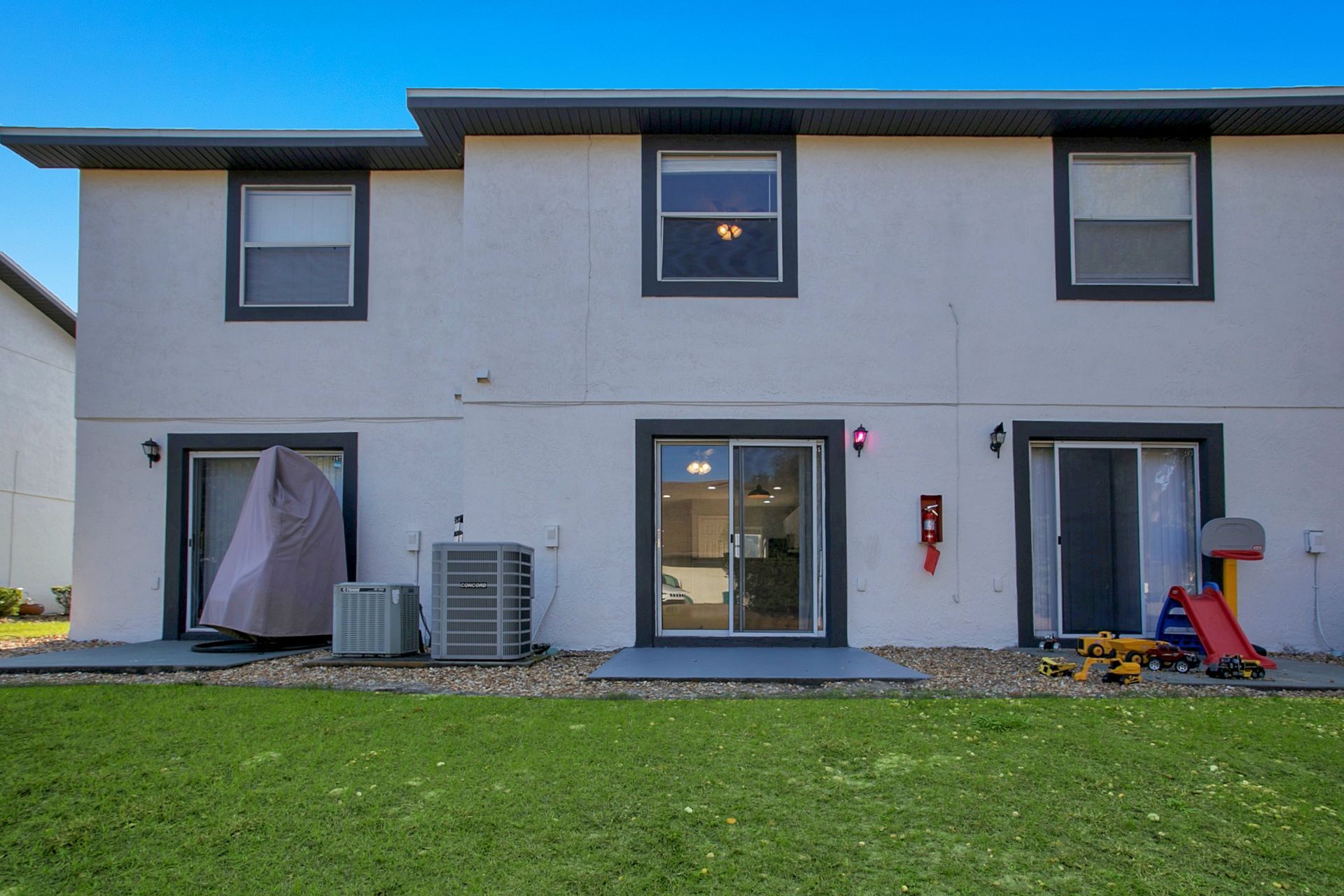 The back of a apartment building with a sliding glass door and a playground in the backyard.