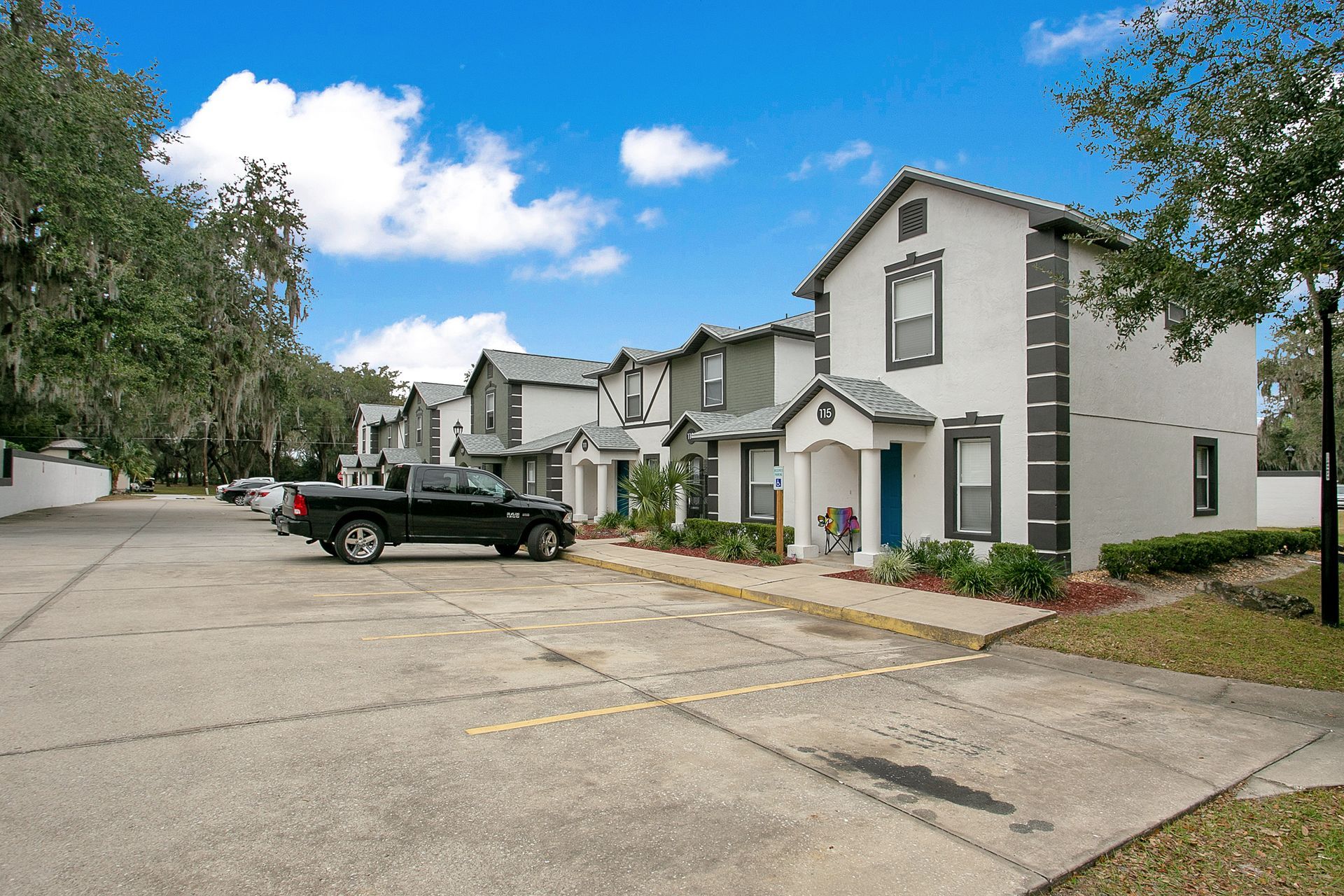 A black truck is parked in front of a row of apartment buildings