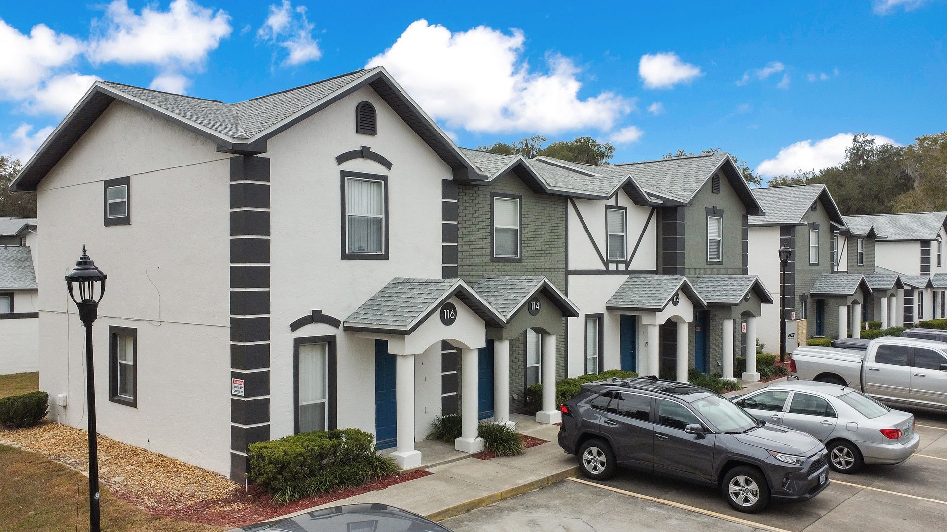 A row of apartment homes with cars parked in front of them.