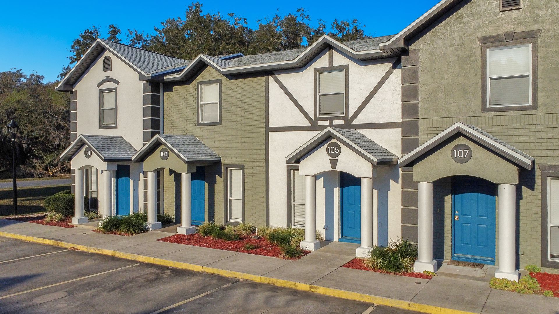 A row of townhomes with blue doors are lined up next to each other.