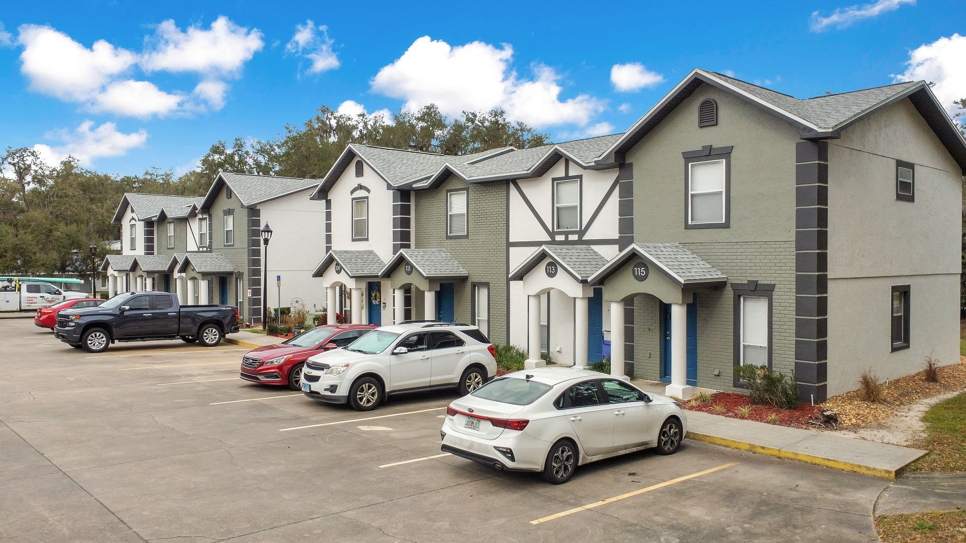 A row of apartment townhomes with cars parked in front of them.