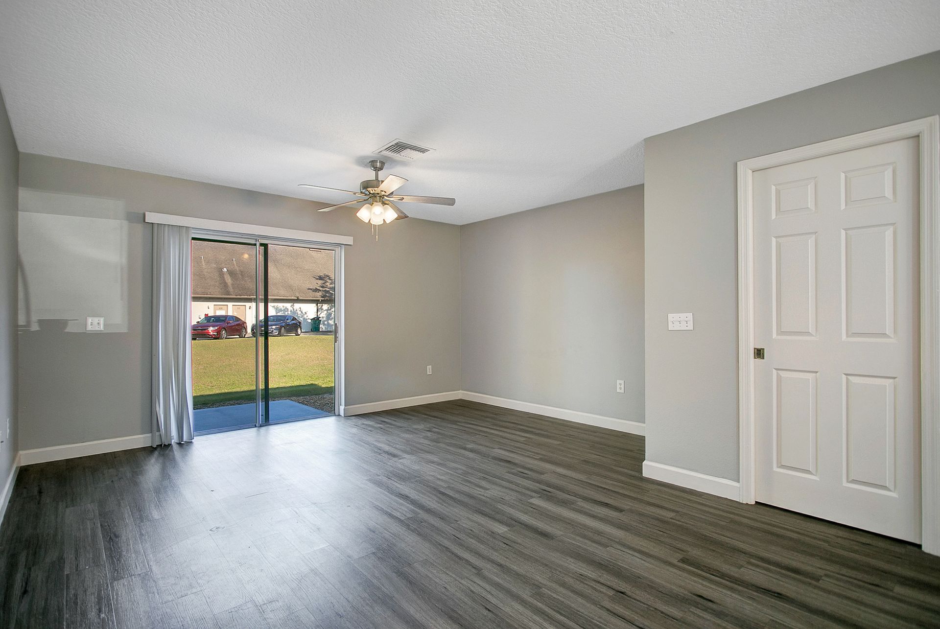An empty living room with hardwood floors and a ceiling fan.
